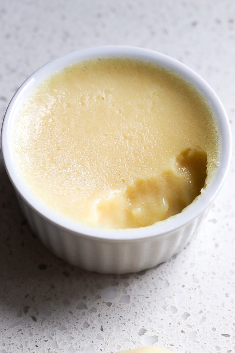 Side view of homemade vanilla protein pudding in small white ramekin.