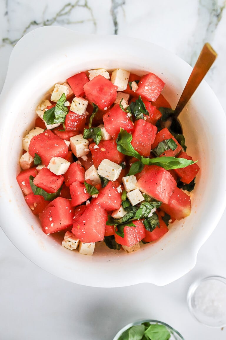 Top down view of watermelon feta basil salad with gold spoon.