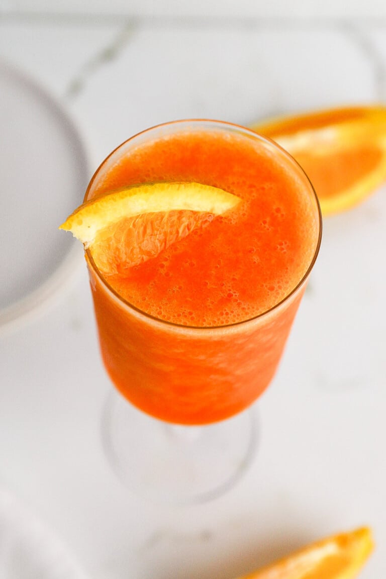 Top down view of aperol spritz in wine glass with orange slice inside.