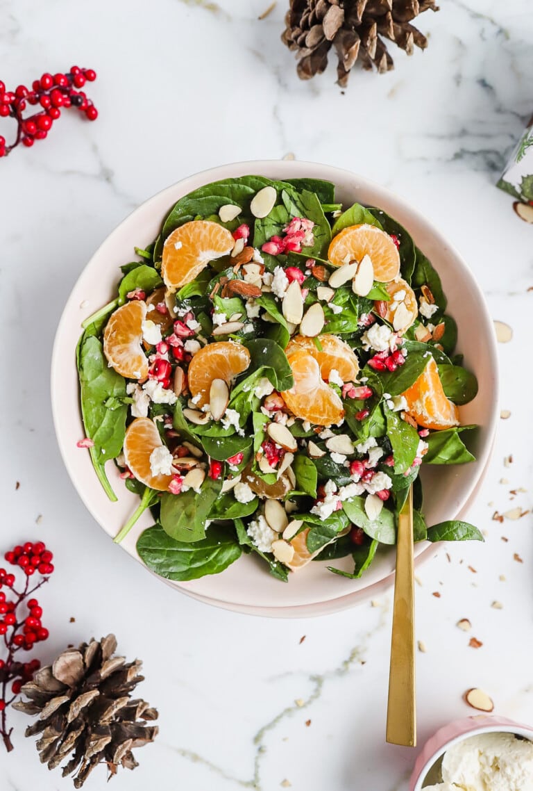 Top down view of beautiful christmas salad with spinach and mandarin oranges in white bowl.