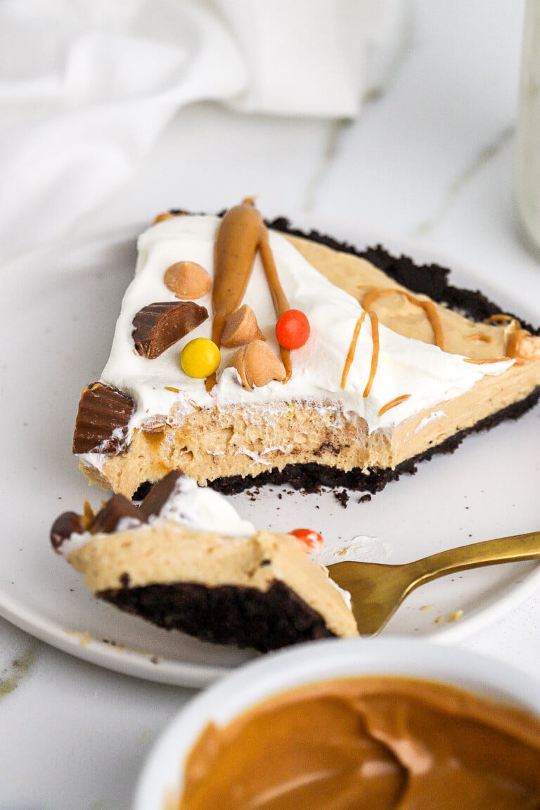 Side angle of bite shot of chocolate peanut butter pie with cool whip on top.