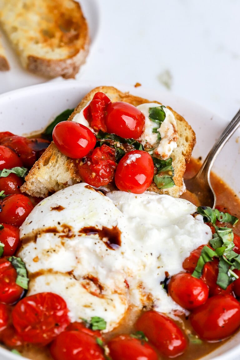 Side angle of easy tomato burrito salad in white bowl with sourdough piece on the side.