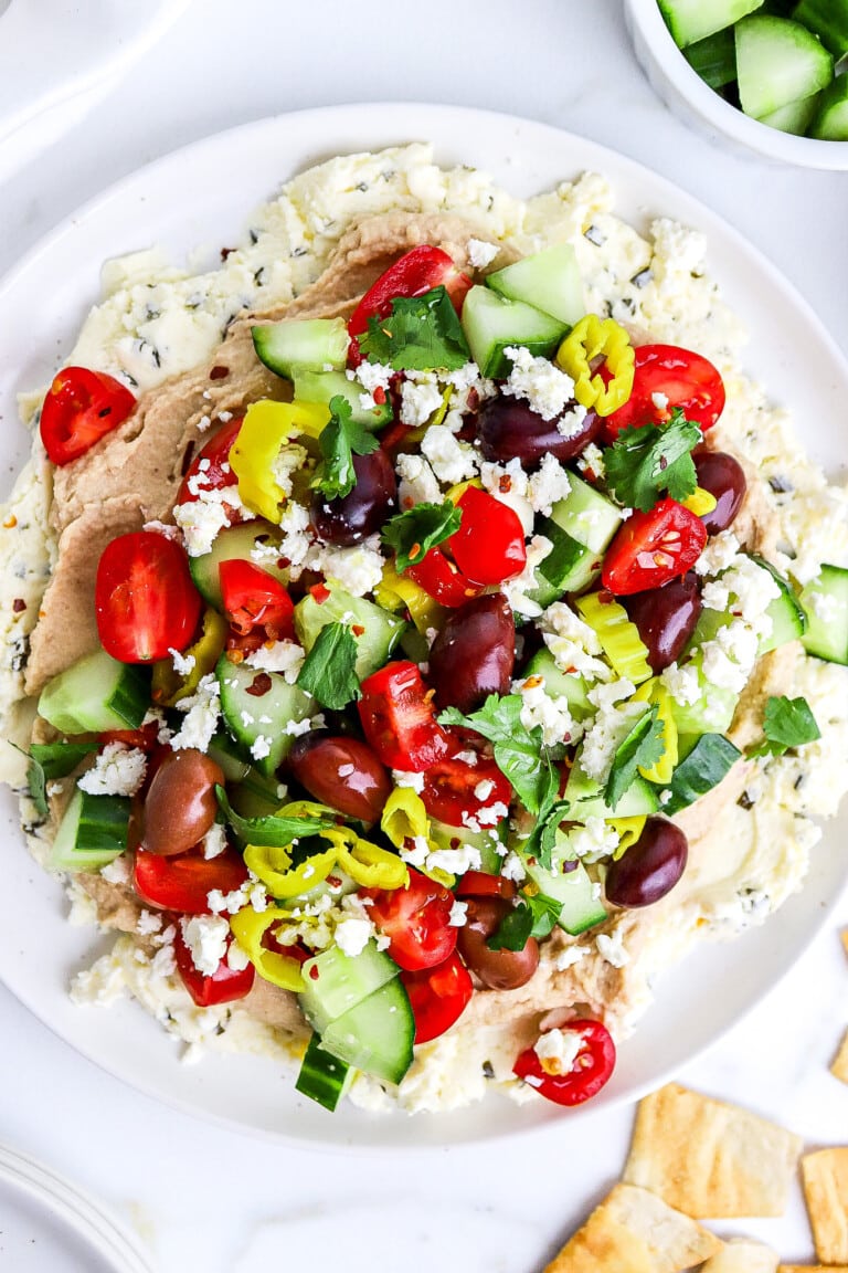 Top down view of homemade Mediterranean dip with fresh veggies on top.