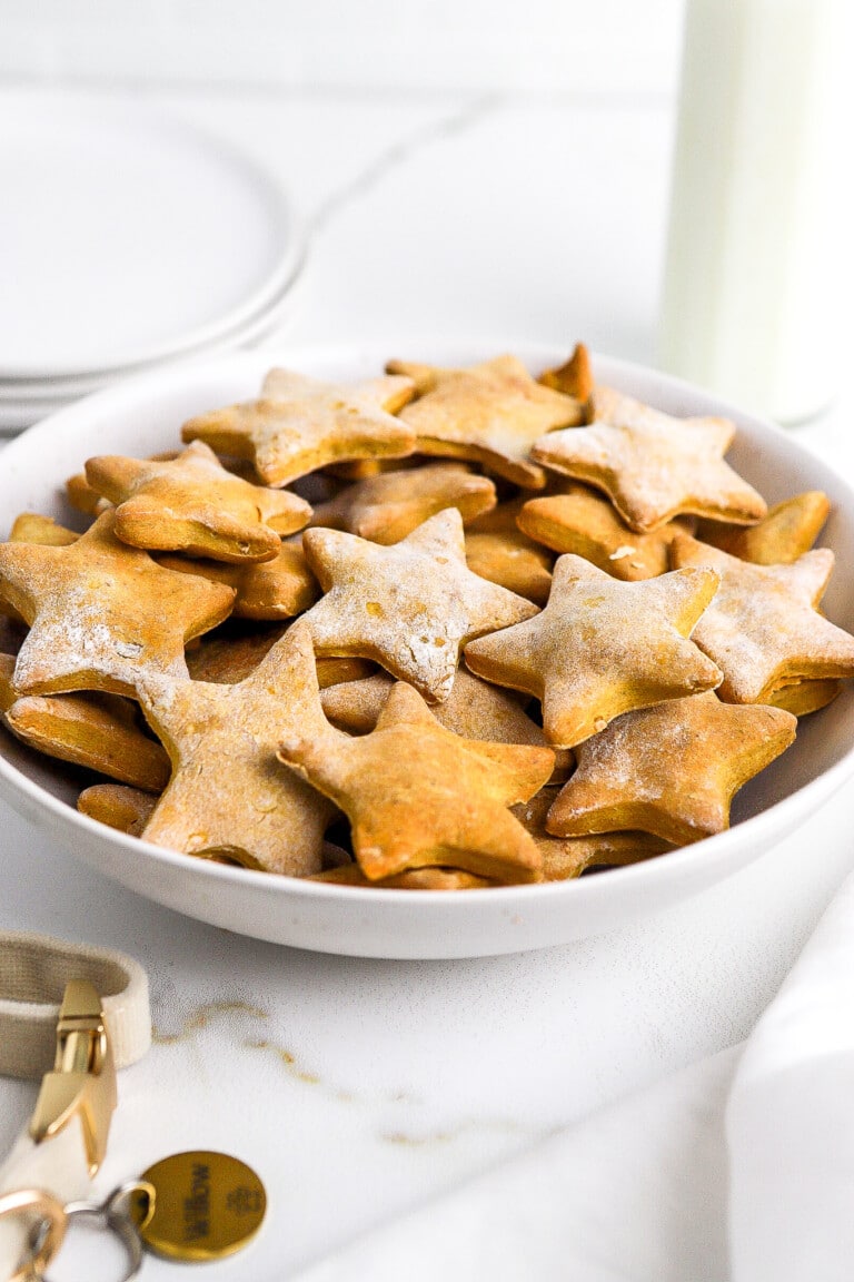 Side view of homemade pumpkin dog treats in star shapes in white bowl.