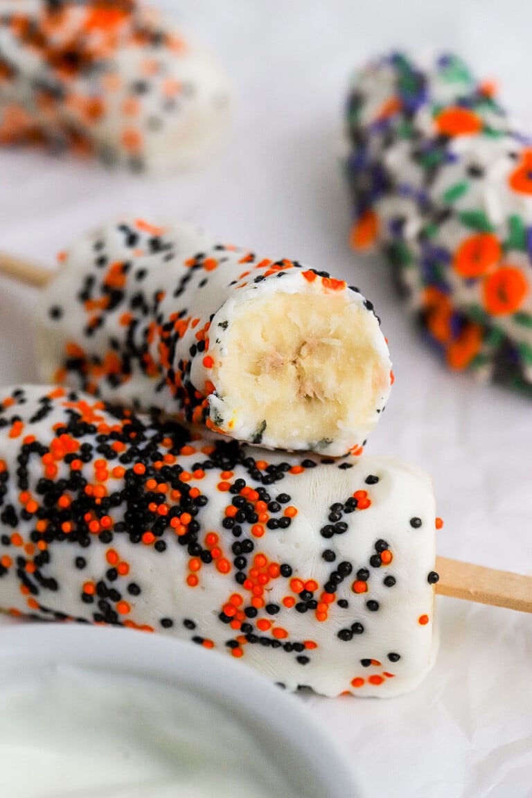 Bite shot of healthy halloween yogurt banana pops stacked on top of one another.