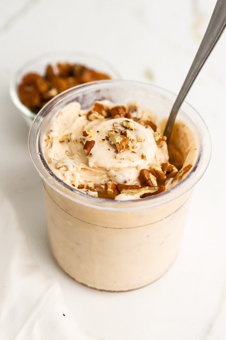 Side angle of keto butter pecan ice cream in ninja creami pint with silver spoon.