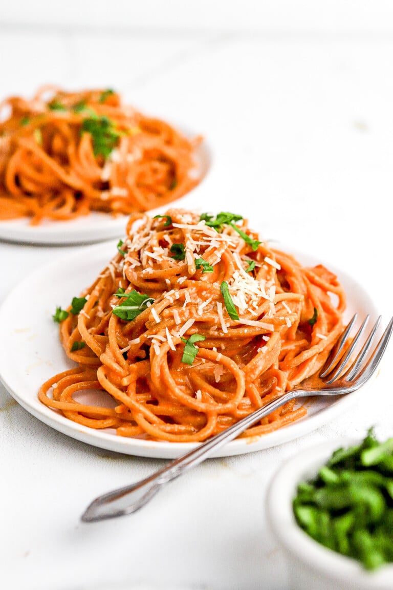 Side view of creamy tomato cottage cheese pasta with fresh herbs and parmesan cheese.