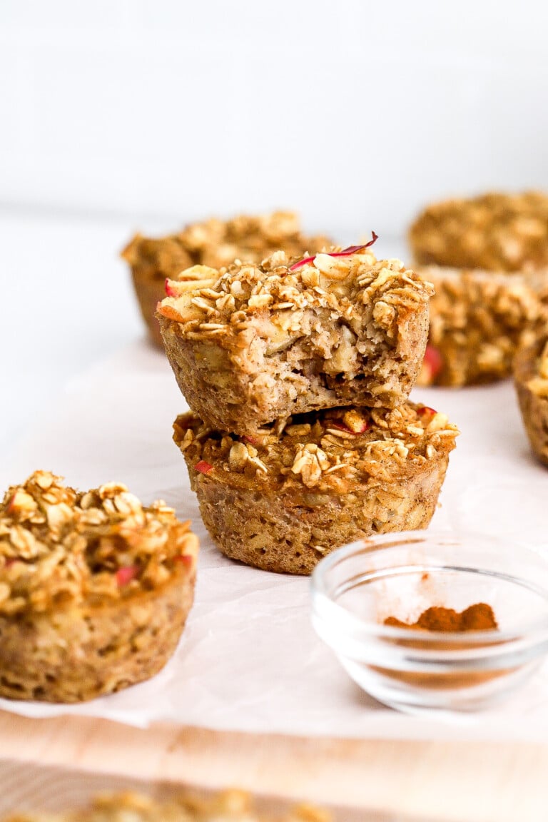 Easy apple oatmeal cups stacked on top of one another with ground cinnamon in a small bowl in the foreground.