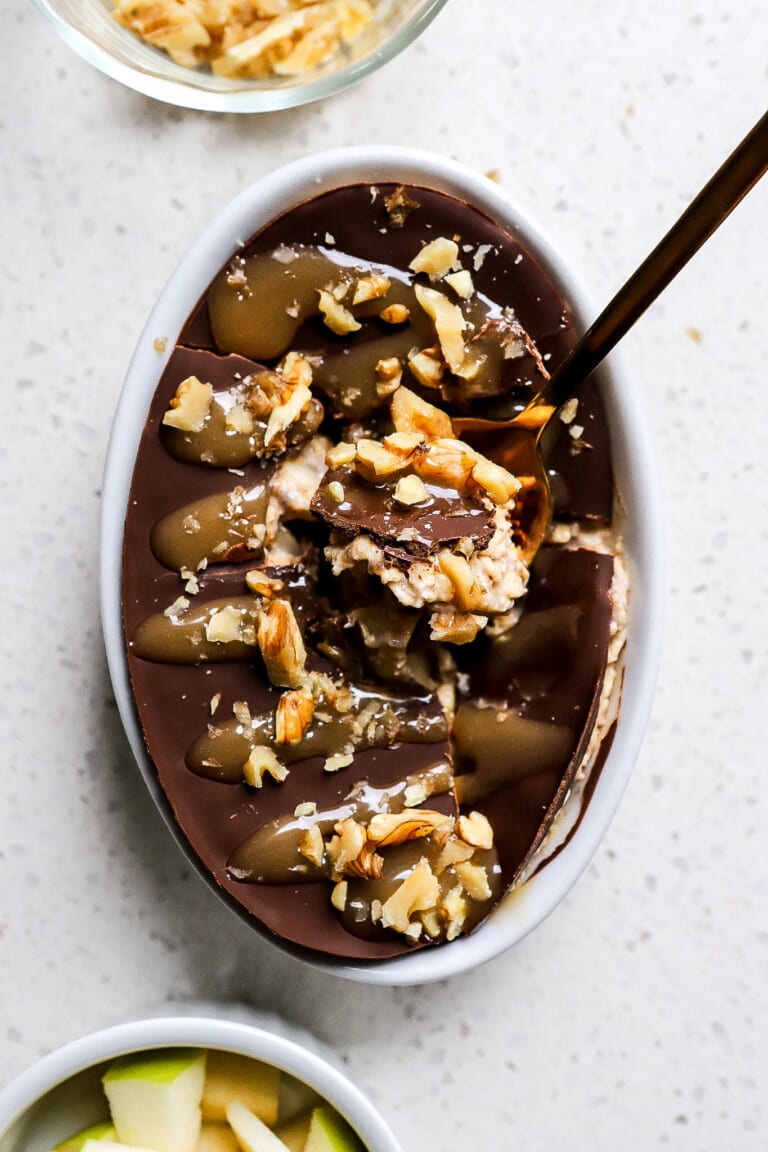 Top down view of candy apple overnight oats with chocolate shell and spoon inside of the oats.