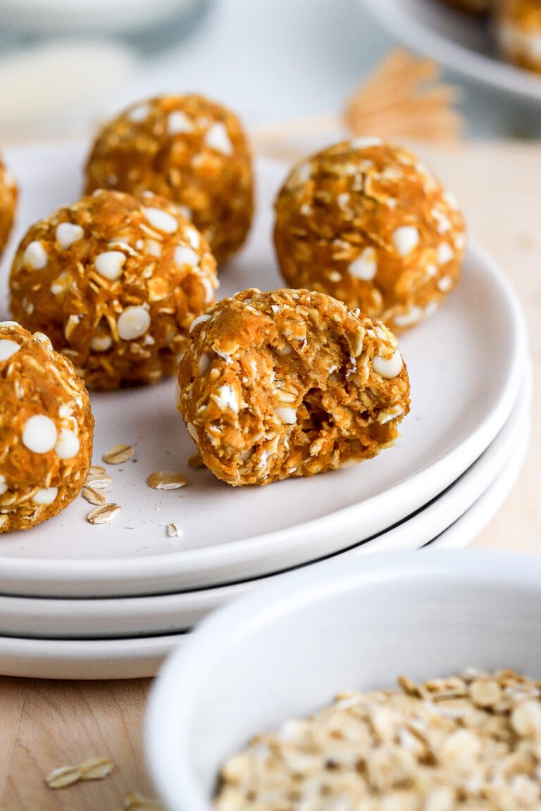 Side view of a bite shot of pumpkin pie energy balls on small white plate.