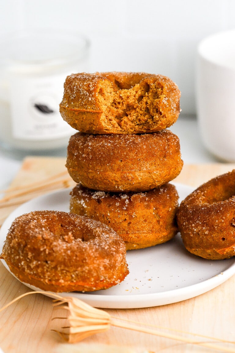 Cinnamon sugar coated donuts stacked on top of one another on small white plate.