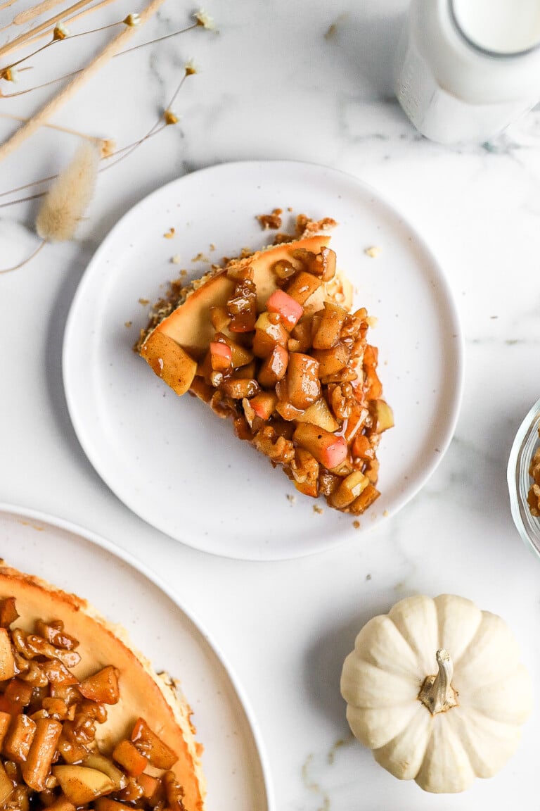 Top down view of a slice of apple pecan cheesecake on small white plate.