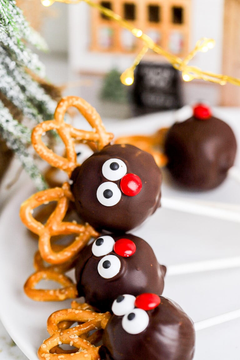 Close up view of Christmas reindeer cake pops with pretzel antlers and candy eyeballs.