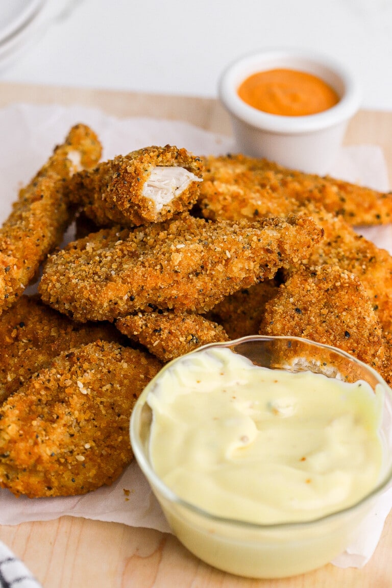 Side view of crispy air fryer chicken tenders with honey mustard sauce in foreground.