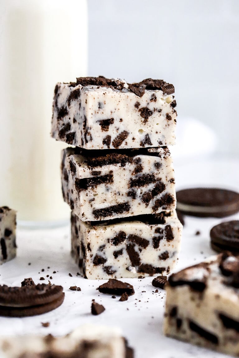 Front facing view of Oreo fudge pieces stacked on top of one another with a glass of milk in background.