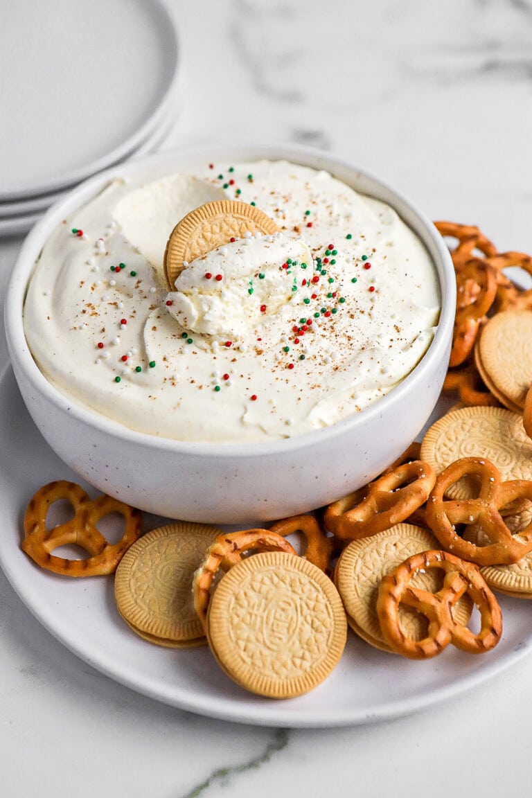 Side angle of easy eggnog dip with a cookie inside the dip and christmas sprinkles on top.