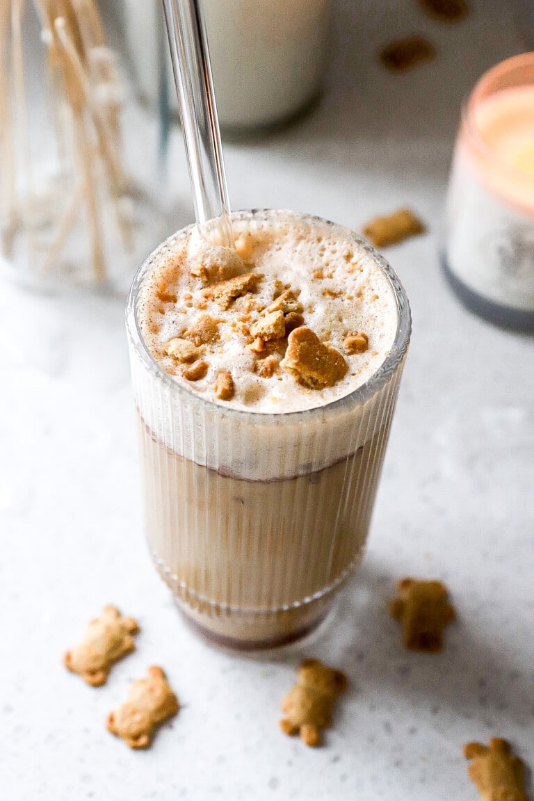 Side angle of espresso teddy graham latte recipe in glass with crushed teddy grahams on top.