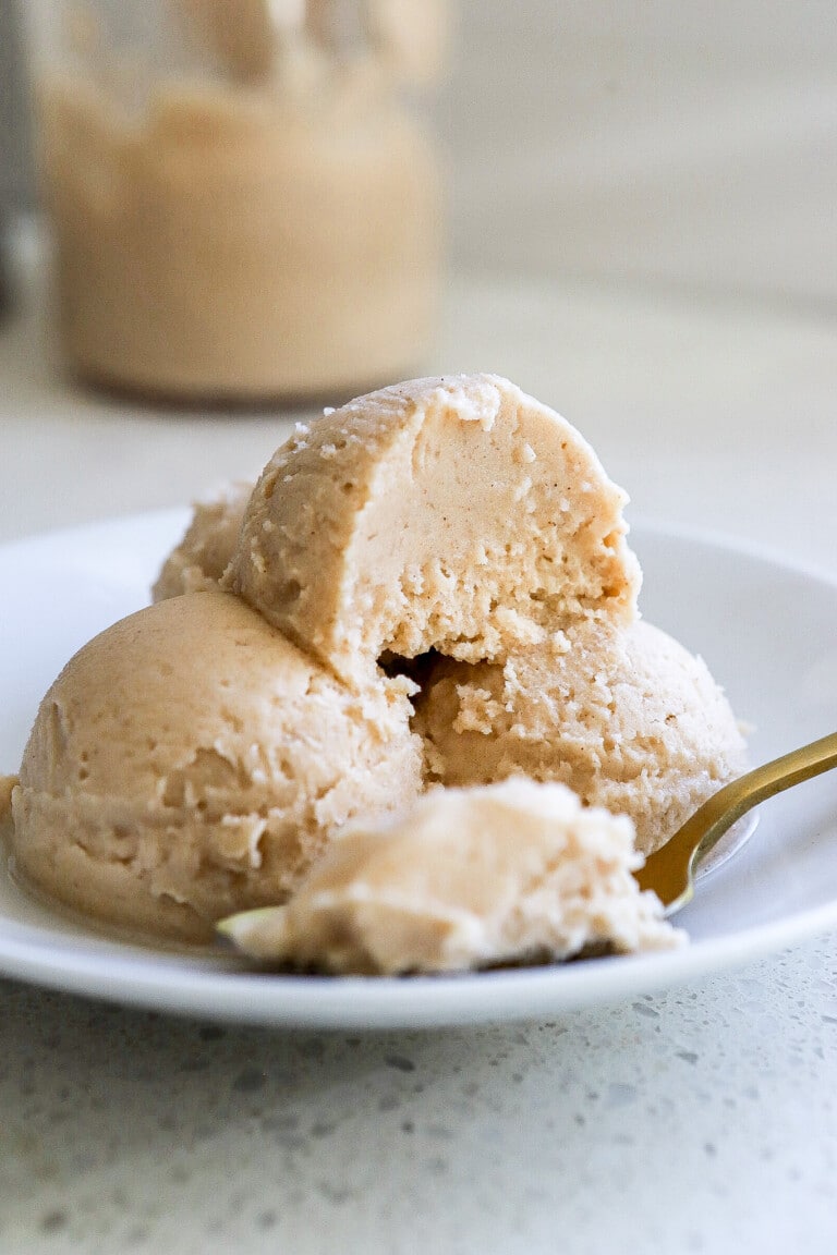 Side view of homemade protein ice cream in small white bowl with gold spoon.