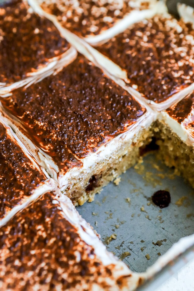 Side angle of tiramisu protein baked oatmeal in baking pan with greek yogurt topping and cocoa powder dusted on top.