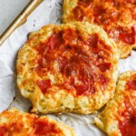 Cottage cheese pizza buns topped with marinara, mozzarella, and pepperoni on a baking sheet