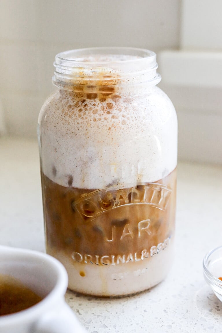 Side angle of an iced protein coffee recipe in a mason jar with layers.