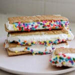 Close up view of birthday cake frozen protein s'mores on a white plate and sprinkles.
