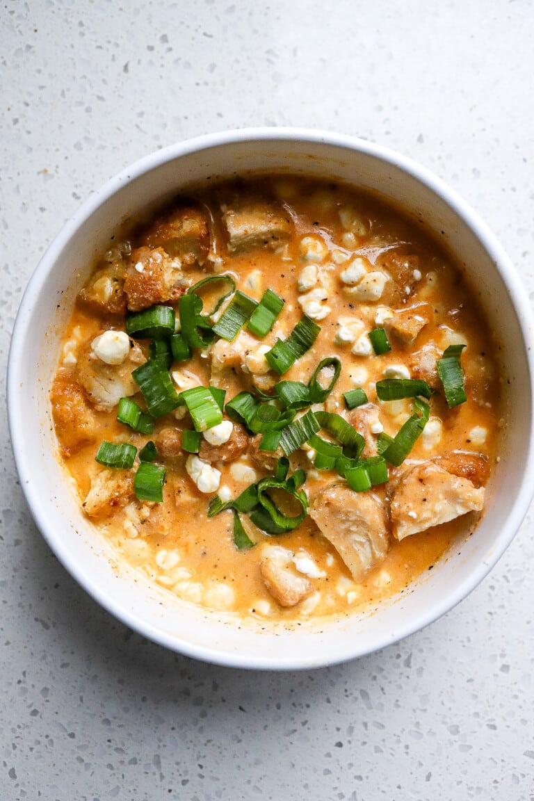 Top down view of buffalo chicken cottage cheese bowl with green onions on top.