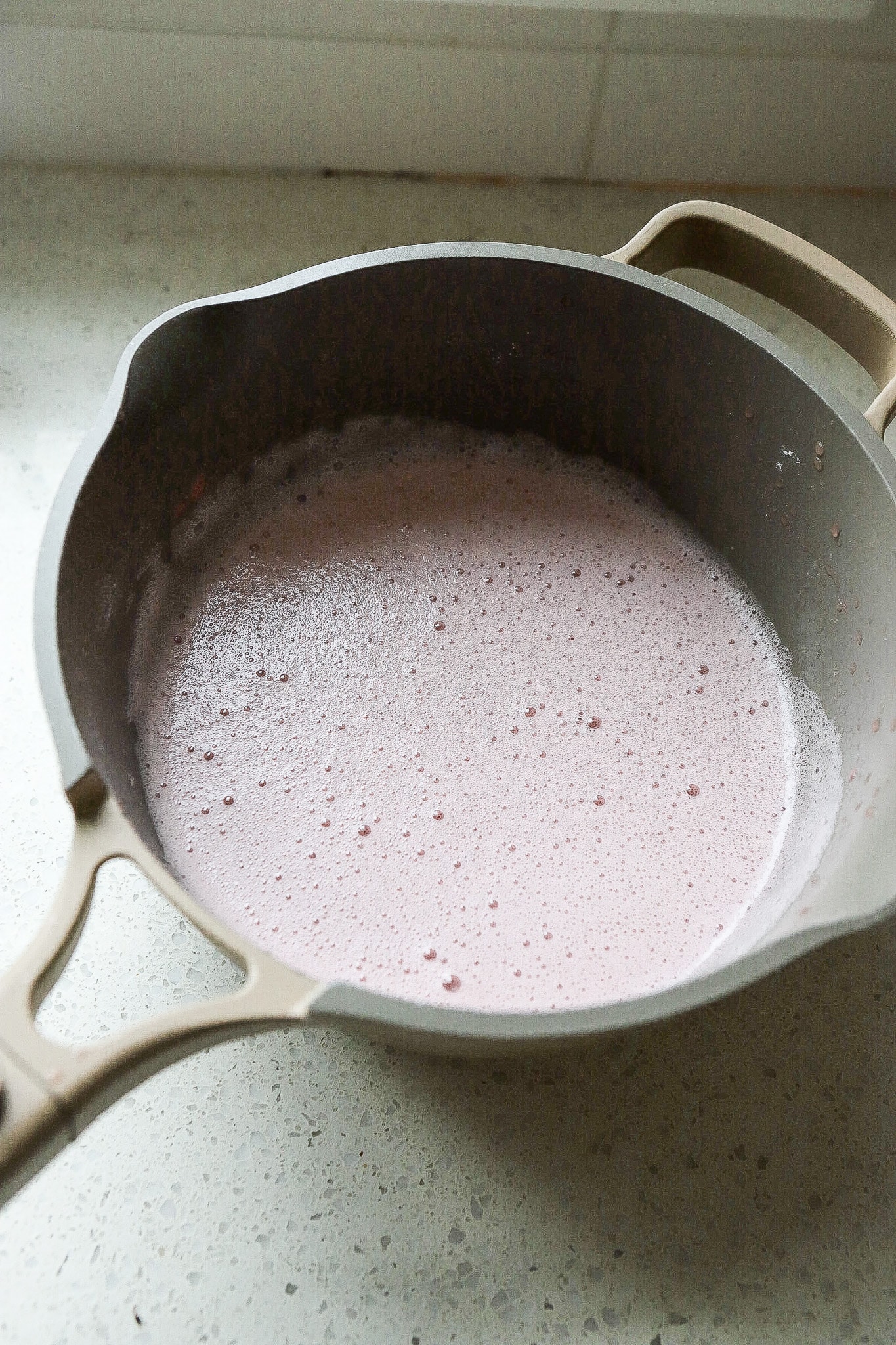 Side angle of liquid mixed with gelatin in a small saucepan.