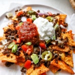 Side angle of air fryer protein nachos with greek yogurt and salsa on top.