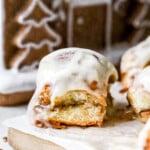 Side angle of hawaiian roll cinnamon rolls with gingerbread house in background.