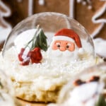 Front facing view of snow globe cookies with edible santa and a red bow inside.