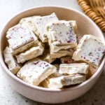 Squares of protein white chocolate in pink small bowl.