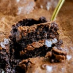 Side angle of brownie pudding with a gold spoon digging in.