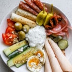 Top down view of savory girl snack plate with cottage cheese, tzatziki, turkey slices, and salami.