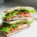 Side angle of high protein chicken flatbread loaded up with fresh veggies and salami.