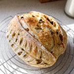 Side angle of rosemary olive garlic sourdough loaf on cooling rack.
