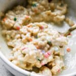 Side view of rice krispies mixed with protein powder and milk in small white bowl.