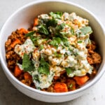 Side close up view of street corn sweet potato beef bowls with fresh cilantro on top.