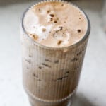 close up of creamy banana milk latte in glass with bubbles