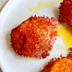 Crispy cheese crusted eggs on white plate with yolk
