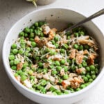 Girl kibble bowl of diced chicken and green peas topped with grated parmesan